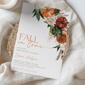 May include: A white invitation card with the text "FALL in love" in brown script, decorated with watercolor pumpkins and floral elements. The card is for a bridal shower in honor of Emma Wilson.