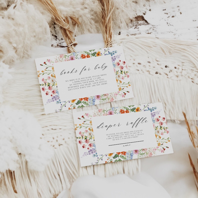 May include: Two rectangular baby shower cards with floral borders. One card reads "Books for Baby" and the other says "Diaper Raffle". The cards have a white background with colorful flowers in shades of pink, blue, orange, and green.