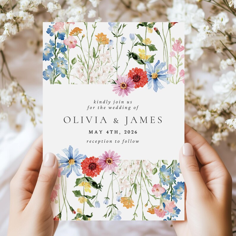 May include: A rectangular wedding invitation card featuring watercolor illustrations of colorful wildflowers at the top and bottom. The text reads: kindly join us for the wedding of OLIVIA & JAMES MAY 4TH, 2026 reception to follow.