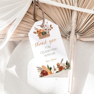 May include: A white gift tag with a brown leather string features a watercolor illustration of pumpkins, gourds, and fall foliage. The tag reads "thank you for celebrating with me" in copper-colored script, with a personalized name at the bottom.