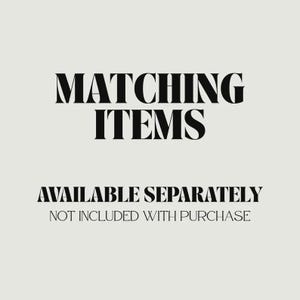 May include: A graphic with the words "MATCHING ITEMS" in a bold, serif font, followed by "AVAILABLE SEPARATELY" and "NOT INCLUDED WITH PURCHASE" in a smaller font, all in black on a light beige background.