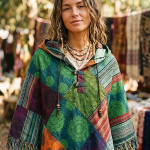 Könnte beinhalten: Ein Kapuzenponcho aus Patchwork in Grün-, Orange-, Lila- und Rottönen. Der Poncho hat ein geometrisches Muster und Fransen am unteren Saum. Die Kapuze hat Kordelzüge mit Holzperlen. Der Stil ist böhmisch.