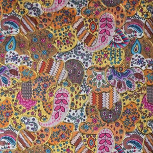 May include: A colourful textile with a patchwork design. The fabric features paisley and floral patterns in shades of gold, orange, pink, yellow, and brown. The design is outlined with gold trim, creating a visually appealing pattern.