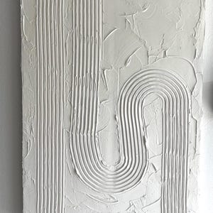 Może przedstawiać: Białe, fakturowane, abstrakcyjne malarstwo z wypukłymi liniami i krzywymi. Projekt przypomina nowoczesne dzieło sztuki.