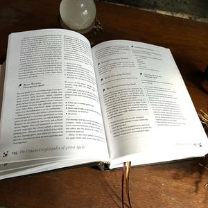 K&ouml;nnte beinhalten: Offenes Buch mit wei&szlig;en Seiten und schwarzem Text. Das Buch tr&auml;gt den Titel "The Element Encyclopedia of 5000 Spells". Das Buch ist auf einer Seite &uuml;ber "Basic Botany Fumigation Spell" und "Mandrake Cleansing Spell" ge&ouml;ffnet.