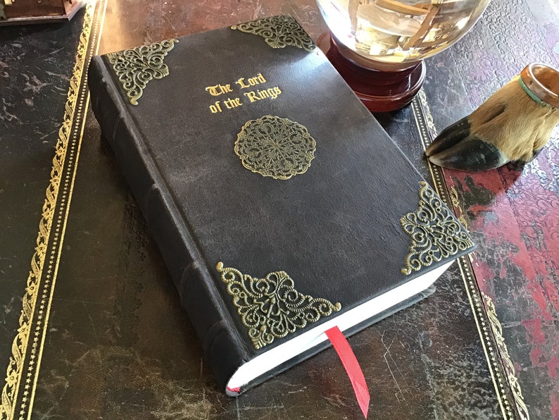 An ornate handmade leather binding with filigree brass corners and gold leaf for the book, the Lord of the Rings.