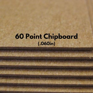 May include: Close-up of a stack of 60 point chipboard, which is 0.060 inches thick. The chipboard is a light brown color and has a slightly rough texture.
