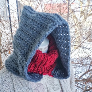 May include: A hooded scarf in a dark blue color with a red crocheted scarf underneath. The scarf is made of yarn and has a textured pattern.