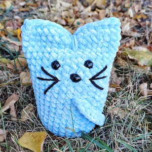 May include: A light blue crocheted cat toy with black embroidered eyes and whiskers.
