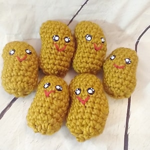 Pode incluir: Seis brinquedos de pelúcia de crochê em forma de batatas fritas com rostos sorridentes. As batatas fritas são de cor amarelo mostarda com olhos pretos e bocas sorridentes vermelhas.