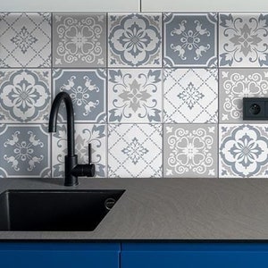 Peut inclure: Une crédence de cuisine avec un motif de carreaux blancs et bleus. Les carreaux ont un motif géométrique avec des accents floraux. La crédence est installée au-dessus d'un plan de travail gris foncé avec un évier et une cuisinière noirs.