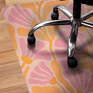 May include: A pink and orange floral patterned chair mat with a silver office chair on top of it.