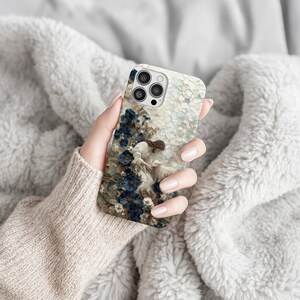 K&ouml;nnte beinhalten: Handyh&uuml;lle mit einem klassischen Gem&auml;lde, das eine Frau und ein Lamm in einem Feld blauer Blumen zeigt. Der Hintergrund ist mosaikartig gestaltet und hat einen Kameraausschnitt.