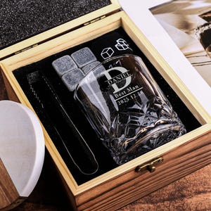 May include: A wooden gift box set with a personalized whiskey glass, ice stones, tongs, and a coaster. The glass is engraved with "DANIEL Best Man 2025.12.28". The coaster is half wood and half white. The box is open, showing the contents.