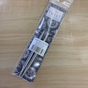 Peut inclure: Deux aiguilles à tricoter interchangeables en argent dans un emballage en plastique. L'emballage est étiqueté "TWIST SS Lace Tips 4" (10 cm) (L) US 9 (5,5 mm) Item No. 7504-9".