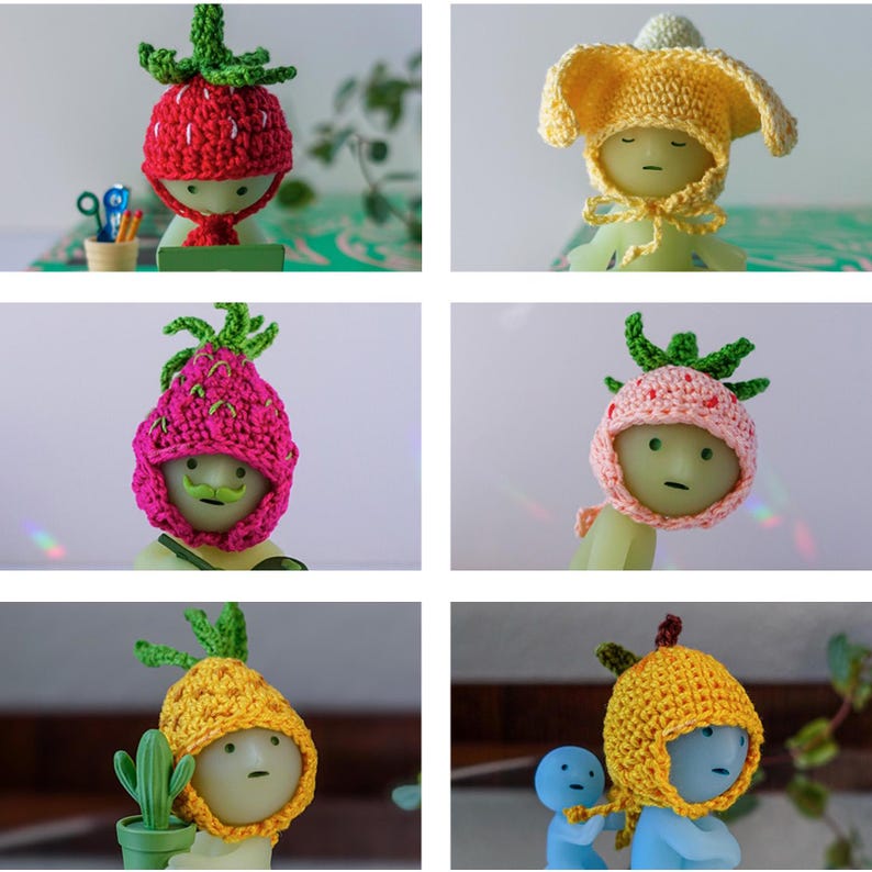 May include: Six crocheted hats in various fruit designs. The hats are pink, yellow, and red with green leaves. The hats are worn by small, white, faceless figures.
