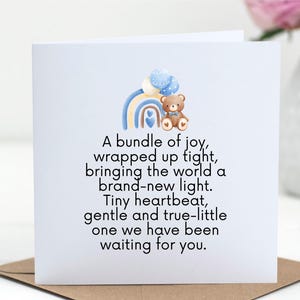 May include: A square greeting card with a baby theme. The card features a watercolor rainbow, a teddy bear, and text that reads "A bundle of joy, wrapped up tight...waiting for you."