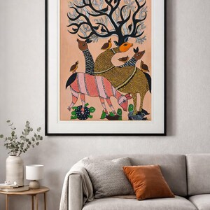 May include: A framed artwork featuring a stylized depiction of animals and birds under a tree. The artwork uses a warm color palette with pink, brown, and green accents. The animals have patterned designs, and the tree has a unique, abstract shape.