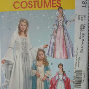 May include: McCall's Costumes pattern M5731 featuring illustrations of princess-style dresses. The pattern includes options for different sizes and styles, with images of the finished garments in white, blue, pink, and red.