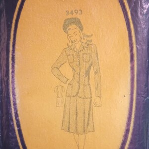 Puede incluir: Sobre de patr&oacute;n de costura vintage con un dibujo de una mujer con traje. El sobre es una mezcla de morado y beige, con el n&uacute;mero 3493 visible. Tambi&eacute;n es visible el texto "MATERIAL REQUIRE".