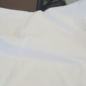 May include: A stack of white fabric, folded neatly. The fabric is smooth and appears to be cotton.