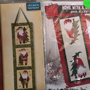 May include: Two Christmas-themed fabric craft patterns. The first pattern is a Santa Trio pattern with three different Santa figures. The second pattern is called "Home with a Gnome" and features a gnome with a Christmas tree. Both patterns are 16 inches by 37.5 inches.