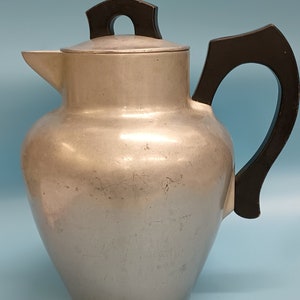 May include: A silver aluminum teapot with a black plastic handle and lid. The teapot has a rounded body and a spout on the side.