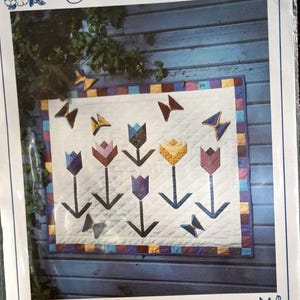 May include: A package for a quilt pattern titled "Garden Fantasy" featuring a floral design with tulips and butterflies. The quilt measures 32 x 38 inches. The package is labeled "Four Corners".