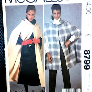 May include: McCall's sewing pattern featuring two women modeling capes. One cape is beige, the other is gray and white plaid. The pattern includes the text "McCall's" and "NANCY HELLER". The pattern number is 8799.