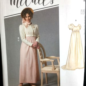 May include: A McCall's sewing pattern featuring a woman in a vintage dress and jacket. The dress is pale pink, and the jacket is white. The pattern includes a drawing of a similar dress. The text "McCall's" is at the top.