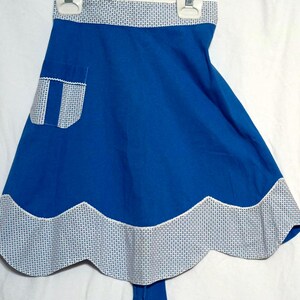 May include: A blue and white apron with a scalloped hem and a white pocket. The apron has a white and blue checkered pattern around the top and bottom.
