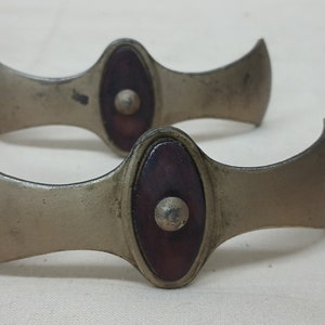 May include: Set of four antique metal and wood drawer pulls. Each pull features a curved, wing-like design with a round, wooden knob in the center.