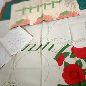 May include: Vintage fabric pieces with printed designs. One piece features a cartoon elf with the text "HOT PAN." Other pieces include floral and geometric patterns in red, green, and peach on a cream background. The pieces are cut with outlines.