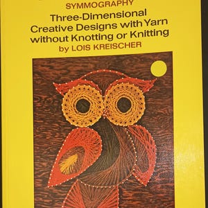 May include: A yellow softcover book titled STRING ART SYMMOGRAPHY Three-Dimensional Creative Designs with Yarn without Knotting or Knitting by LOIS KREISCHER. The cover features a string art illustration of an owl against a dark brown background.