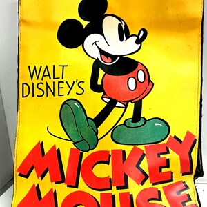 May include: Yellow tote bag featuring a smiling Mickey Mouse illustration. The bag has black handles and the words "WALT DISNEY'S" and "MICKEY MOUSE" in red. Mickey is depicted in his classic outfit with red shorts and green shoes.