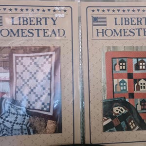 May include: Two quilt patterns, both with the text "LIBERTY HOMESTEAD" at the top. The first pattern is a white and blue quilt with a diamond pattern. The second pattern is a red, white, and blue quilt with a house pattern.