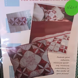 May include: A quilting pattern for a bedroom suite featuring a pillow, bed runner, and curtains. The pattern is called "Tea Leaf Bedroom Suite" and features redwork, machine quilting, and machine embroidery. The pattern is from Poor House Quilt Designs.