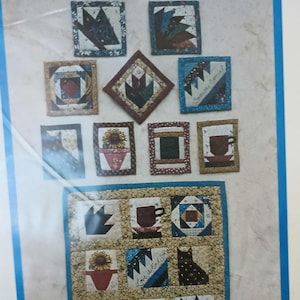 May include: A pattern for a quilt with a variety of designs, including a sunflower, a cup of coffee, a cat, and a paw print. The pattern is titled "Cozy Quilted Pins" and is from The Violet Patch, Inc. in Sandy, Utah.
