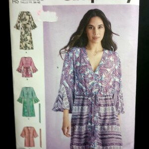 May include: Simplicity sewing pattern S9602 featuring a V-neck tunic with bell sleeves and a drawstring waist. The envelope displays four variations of the garment in different colors and patterns, including a paisley print and solid colors.