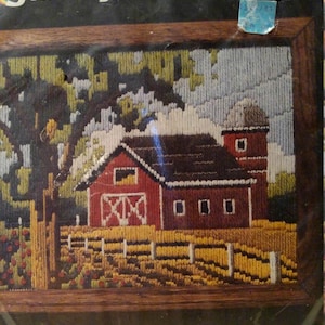 May include: A vintage "Spring Barn" longstitch needlepoint kit. The framed artwork depicts a red barn with a silo, a yellow fence, and a tree. The kit measures 8" x 10". The packaging includes the text "FAST • EASY • FUN".