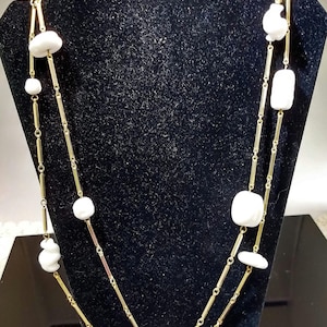 May include: A gold chain necklace with white ceramic beads. The necklace is double-stranded and has a simple design.