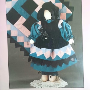 May include: A sewing pattern for a Patience doll, featuring a black and teal dress with pink accents. The pattern is from Pear Blossom Patterns and is number 360. The doll is 24 inches tall.