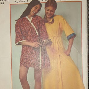 May include: Simplicity sewing pattern number 627, titled "Super Simple" with a price of 75 cents. The pattern features two women wearing yellow and floral print robes. The text "super simple robe in misses' sizes" is printed on the pattern.