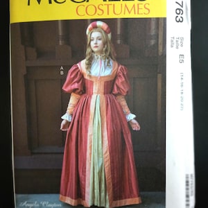 May include: McCall's Costumes sewing pattern featuring a woman in a Renaissance-style gown. The pattern includes a full-length red dress with a light green panel, a matching headpiece, and long sleeves. The pattern is size E5.