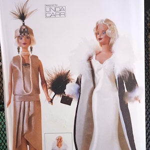 May include: Vogue Craft sewing pattern number 7162 for a doll outfit. The pattern includes two outfits: a white dress with a black fur collar and a beige dress with a beaded necklace. The pattern is designed by Linda Carr.