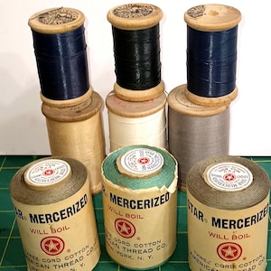 May include: A collection of nine vintage spools of Star Mercerized thread from the American Thread Co. The spools feature wooden ends and paper labels with text including Star Mercerized, Will Boil, and Three Cord Cotton, New York, N.Y.