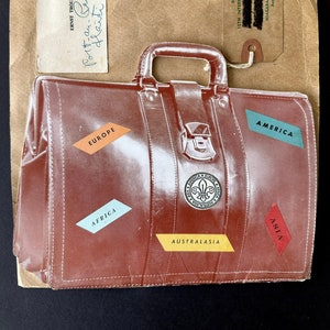May include: A brown leather suitcase with a handle and a metal clasp. The suitcase has stickers on it that say "Africa", "Europe", "Asia", "America", and "Australasia". The suitcase is a symbol of travel and adventure.