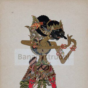 May include: A colorful Javanese shadow puppet, known as a wayang kulit, depicting a character named "Djajad-Rata". The puppet is made of leather and is intricately decorated with gold, red, green, and black paint. The puppet is posed in a dramatic stance, with its arms outstretched and its head tilted to the side.