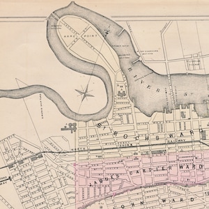 May include: A vintage map of Rochester, New York, showing the city's layout and streets. The map is in black and white with some pink and blue highlights. The map includes the names of the different wards, including the North Shore, Rochester, and Cartier wards. The map also shows the location of the Genesee River and the city's railroad.