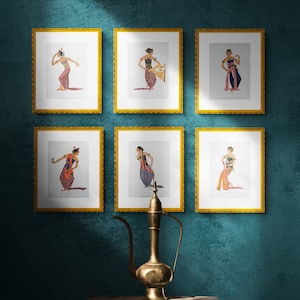 May include: Six framed illustrations of women in traditional Indonesian dance costumes, displayed on a teal wall with a gold-colored metal pitcher on a wooden stool in the foreground.
